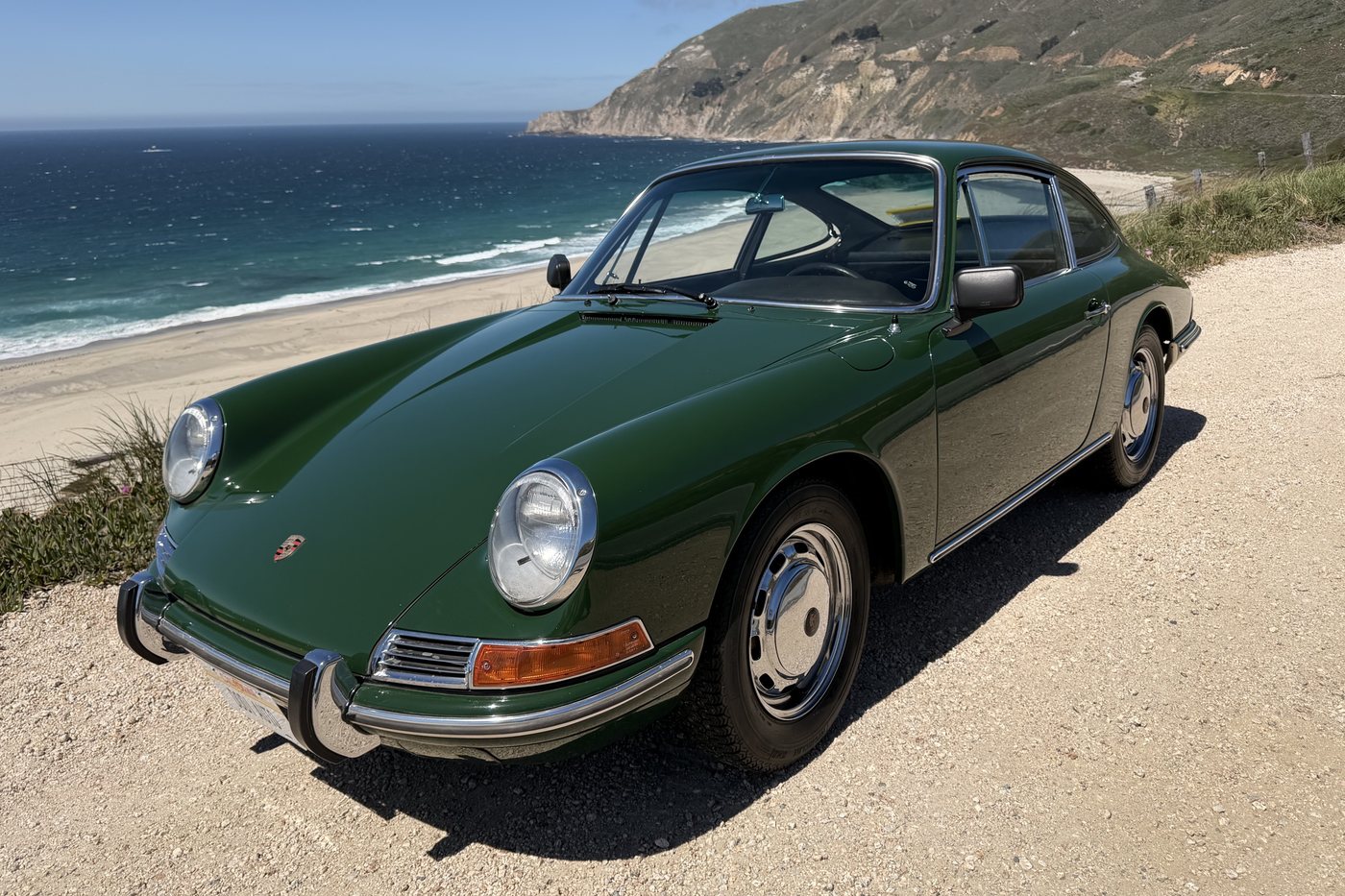 Green 1967 Porsche 912 parked above a beach on the coast