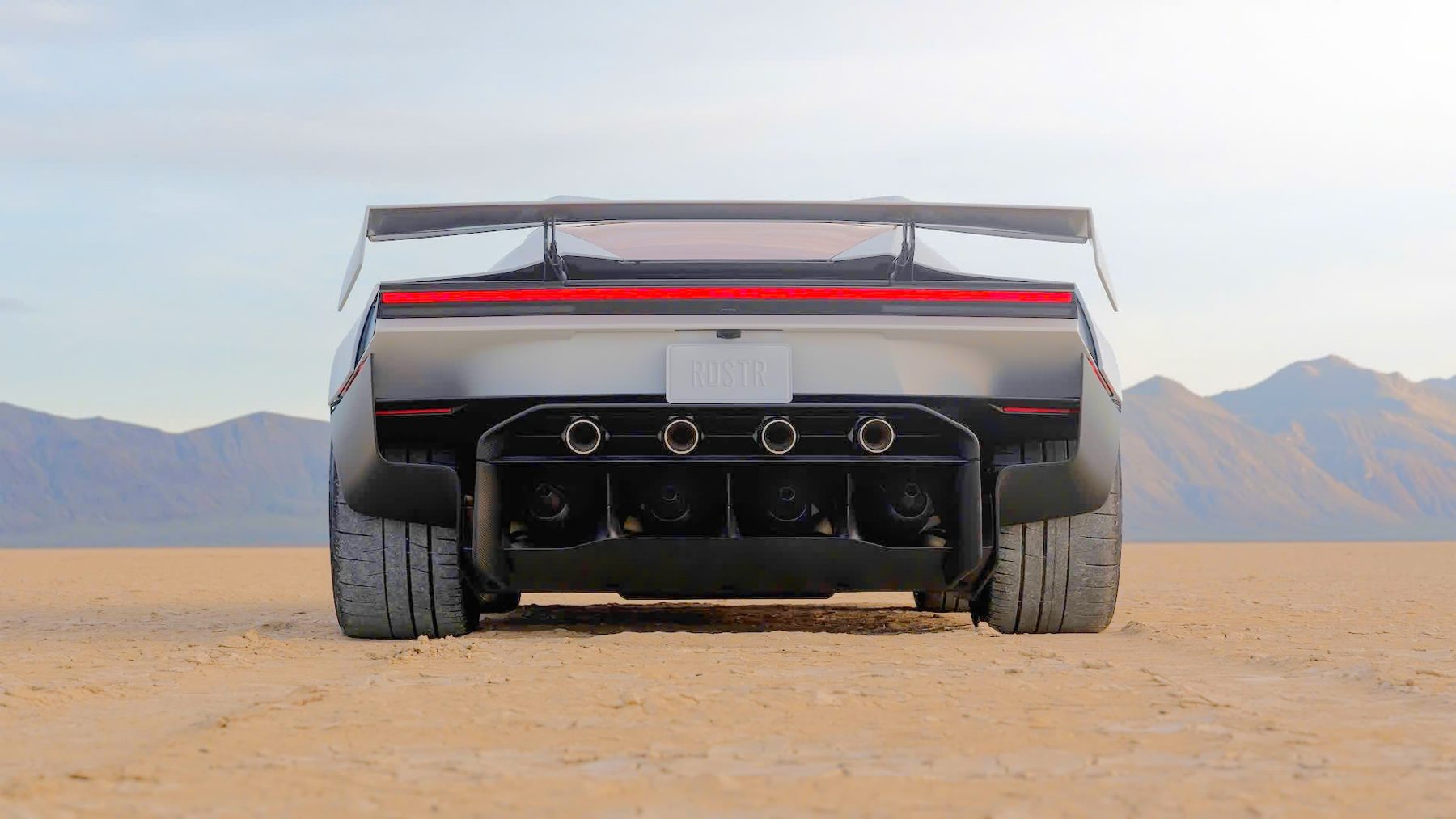 The new Tesla Roadster seen from behind on a dry lake bed, rear wing raised